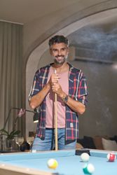 Smiling mature man standing near pool table