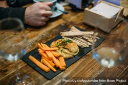 Plate of carrots, pita and hummus on a wooden table 0yaNq0