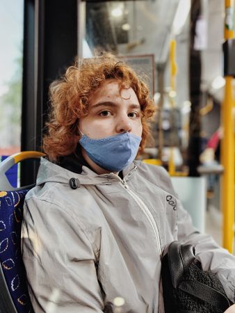 Teenage girl with blue facemask sitting
