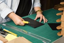 Hands of woman using sharp knife when cutting paper for making notebook