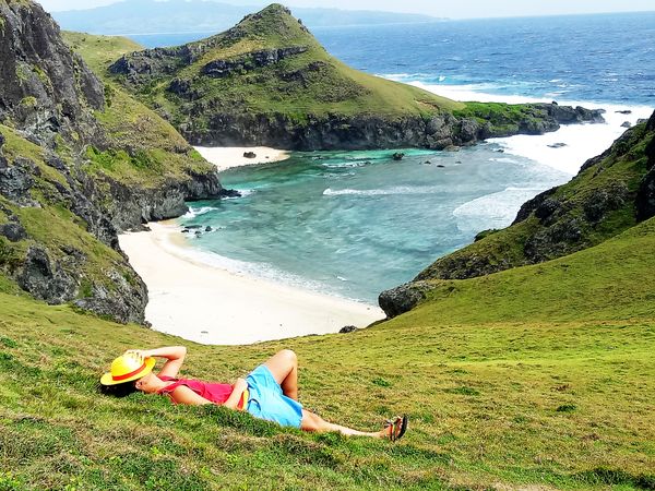 Man lying on grass near ocean