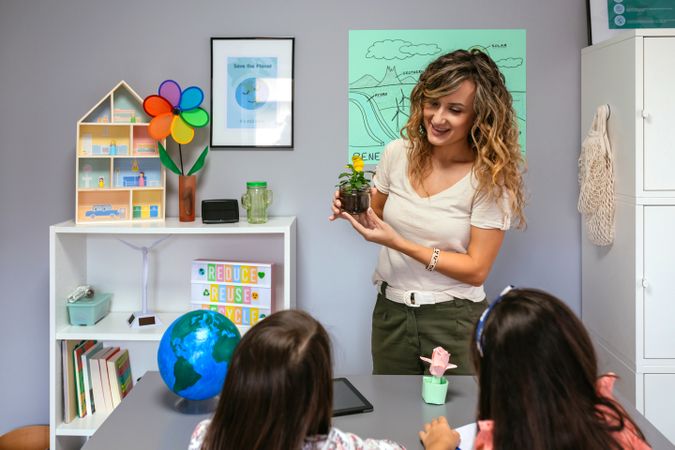 Female teacher showing pansy plant to her students in ecology classroom