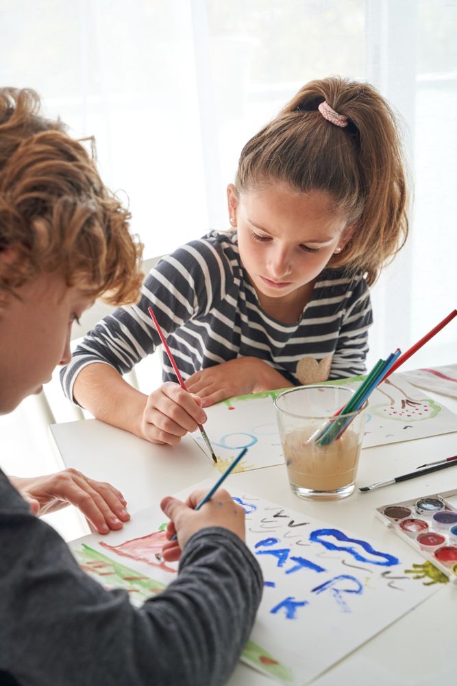 Children painting together at table