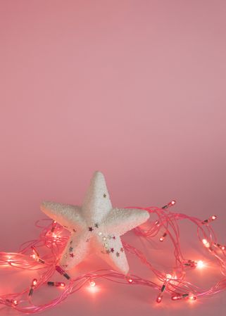 Star surrounded by fairy lights on pink background