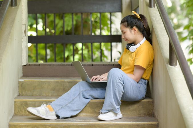 Woman sitting on stairs with a laptop working from home.