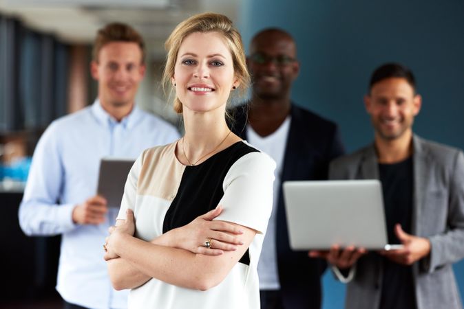 Proud business woman smiling with colleagues in background