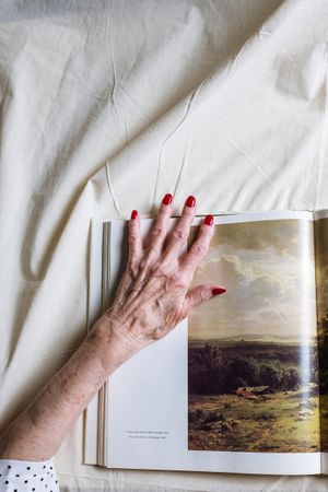 Woman's left hand on a page with natural landscape photo in a book