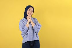 Young Asian Indonesian Woman Wearing Blue Striped Shirt and Navy Hijab Looks Happy