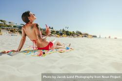Tattooed woman closing her eyes and relaxing at the beach 0Wler5