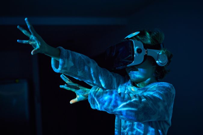 Excited kid gesturing while exploring cyberspace in VR headset