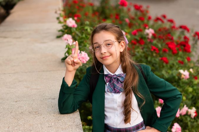 Girl in school uniform smiling and raising finger