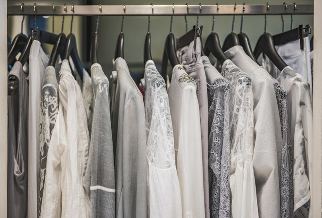 Clothes rack of light and gray shirts and pants in fashion store