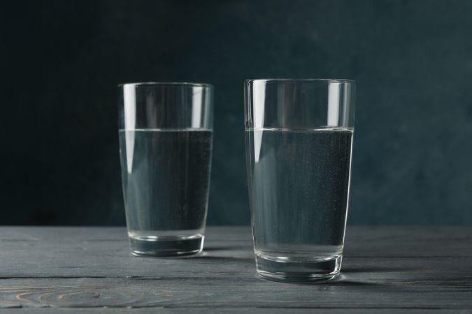 Two glasses of water in dark room on marble table