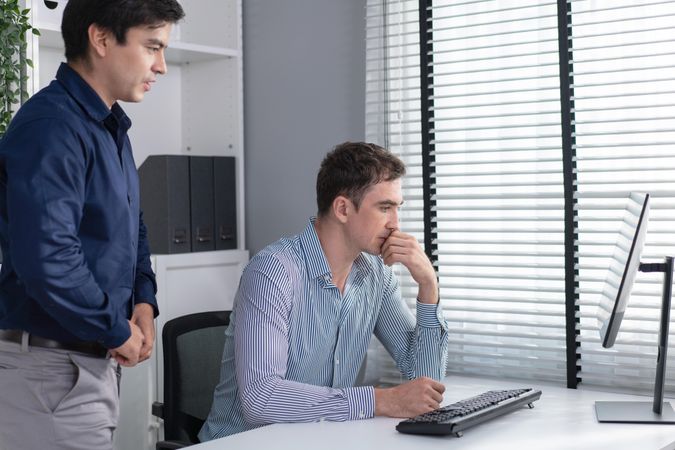 Two corporate coworkers talking together over screen in the workplace
