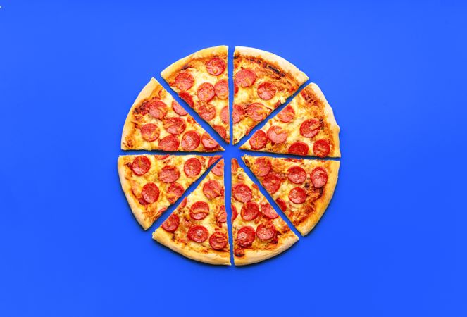 Above view with a delicious pepperoni pizza isolated on a blue background