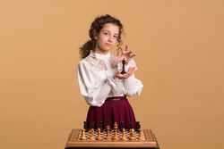 Young girl holding chess piece while posing gracefully.