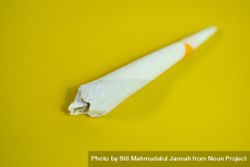 Rolled cigarette on yellow table bxAzBv