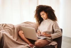 Black female using laptop on sofa