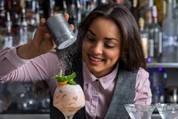 Bartending adding sprinkles of powder over a prepared cocktail