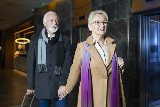 Woman holding hands and leading man down corridor