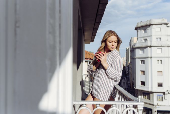 Young cheerful female with cup on terrace