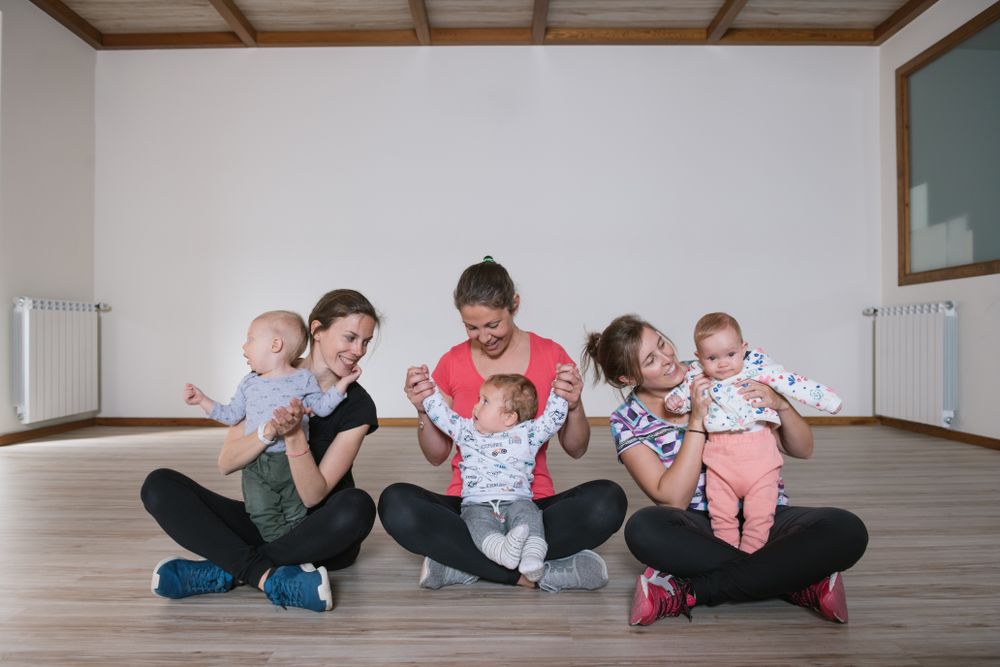 Mothers lifting babies in gym