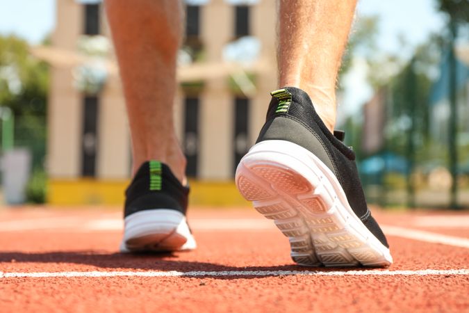 Man in sneakers on red athletic running track, close up