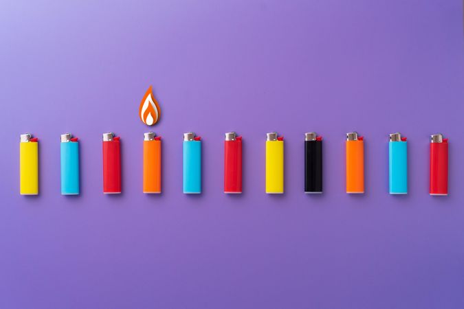 Colorful lighters in a row on purple background