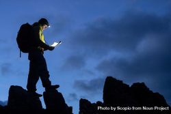 Man in yellow jacket walking on rock formation during nighttime 0VL8G4