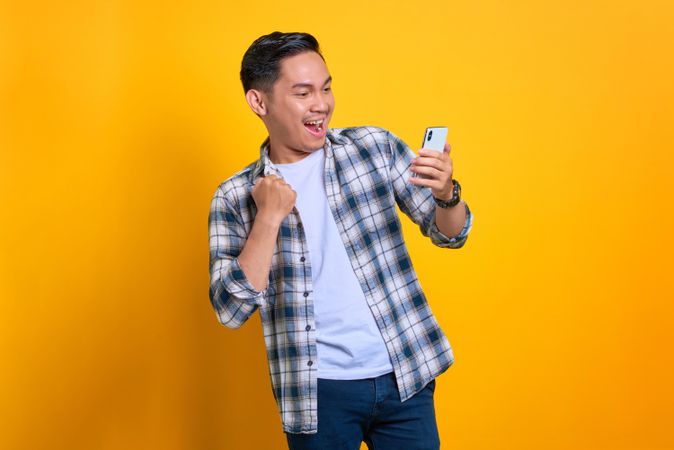 Happy Asian male receiving good news on his phone in studio shoot