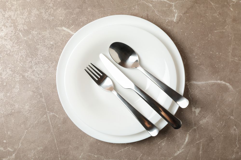 Plates with cutlery on gray background, top view
