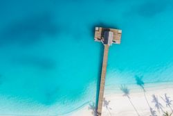 Aerial view of wooden pier on a tropical beach with clear water