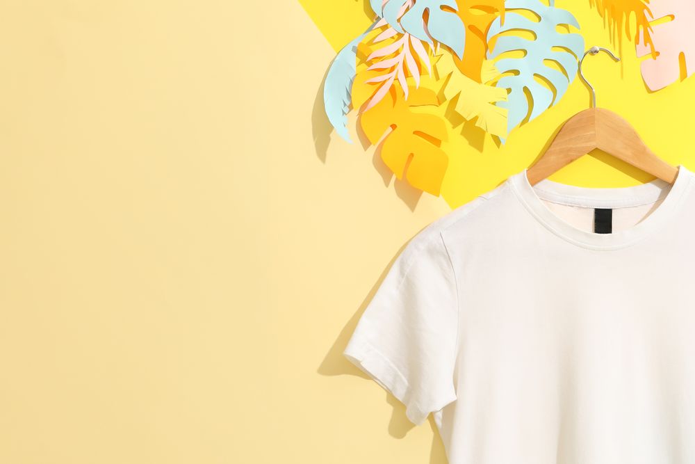 Hanger with blank plain t-shirt on multicolored background, space for text