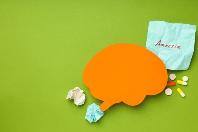 Orange paper cut out of brain on green background, copy space