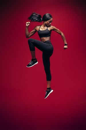 Fitness woman jumping on red background