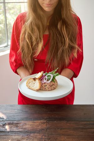 Crop woman with steak tartare on plate