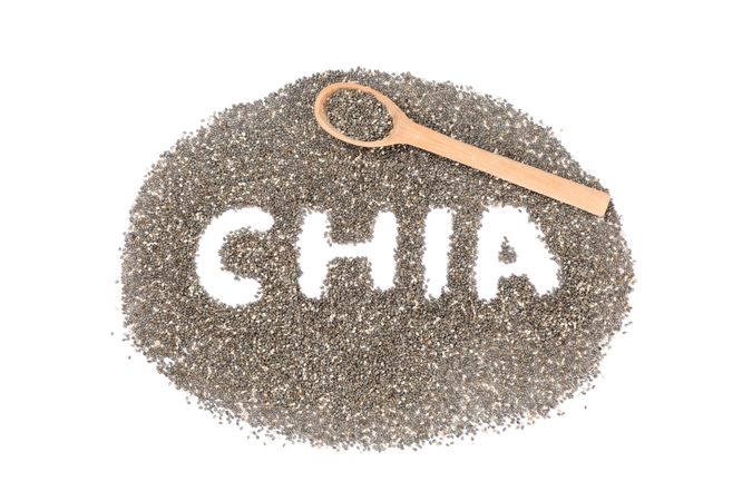 Word Chia, seeds of chia and wooden spoon isolated on blank background