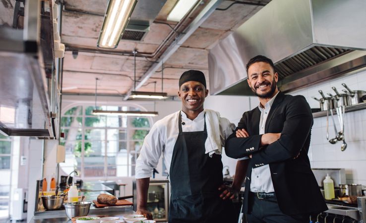 Portrait of restaurant owner with chef in kitchen