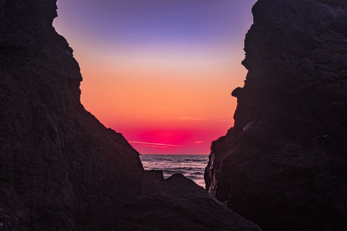 Beautiful sunset seen from behind cliffs of rocky beach