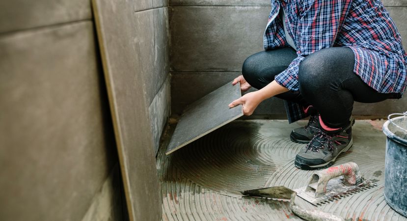 Female builder laying a new tile floor