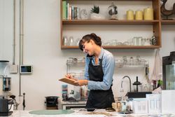 Woman on phone in cafe writing down order