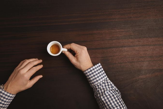 Arms in plaid shirt with single espresso shot