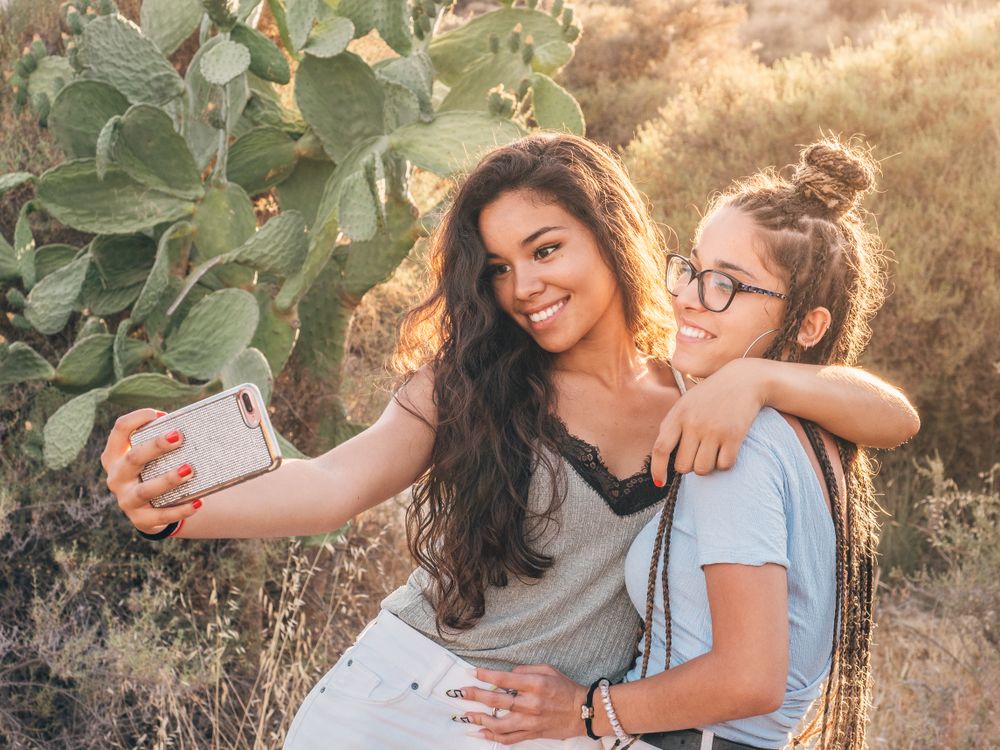 Smiling trendy young women taking selfie at countryside