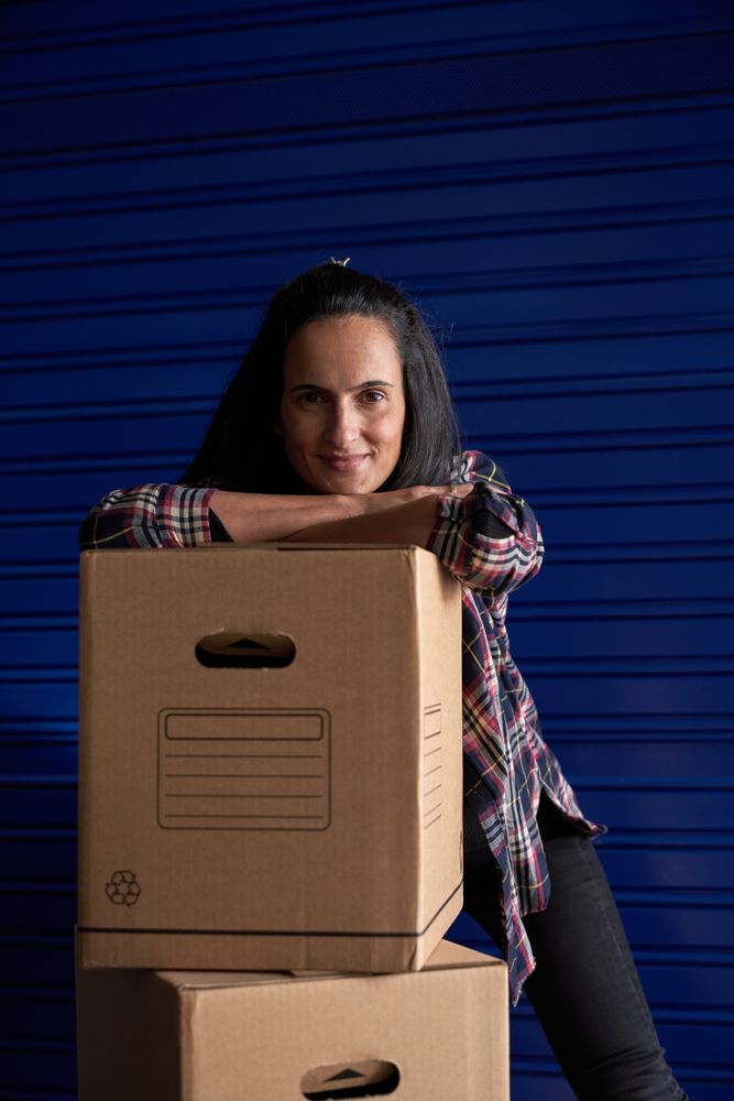 Cheerful woman leaning on pile of boxes