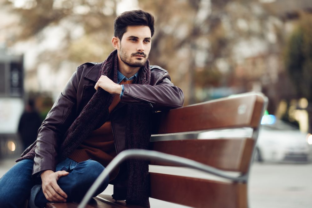 Portrait of man sitting on park bench deep in though