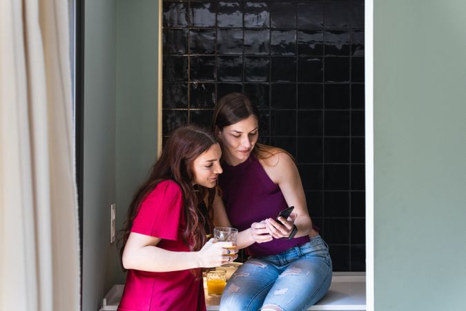 Content women browsing smartphone and enjoying orange juice
