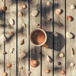 Summer morning coffee surrounded by pattern made of sea shells and rocks