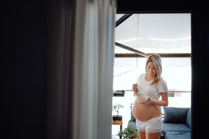 Smiling pregnant woman holding bowl