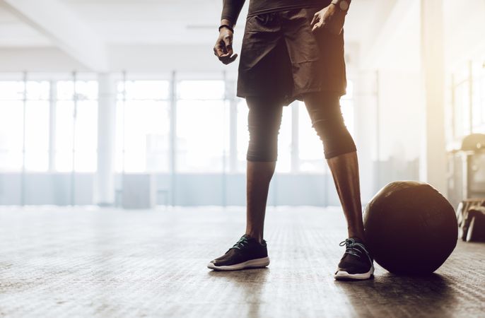 Athletic man standing in the gym beside a medicine ball
