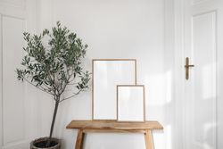 Two blank wooden poster frames in neutral room